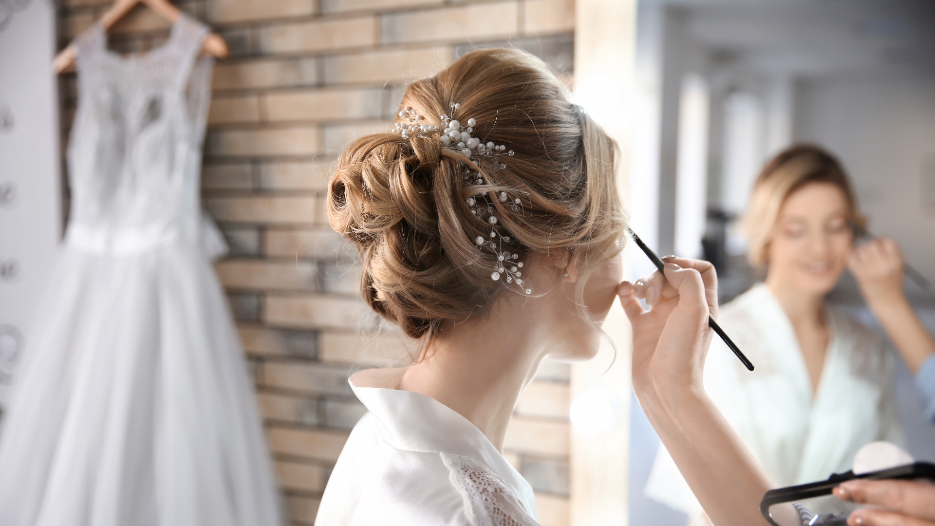 Eine Visagistin schminkt die Braut vor ihrer Hochzeit im Zimmer